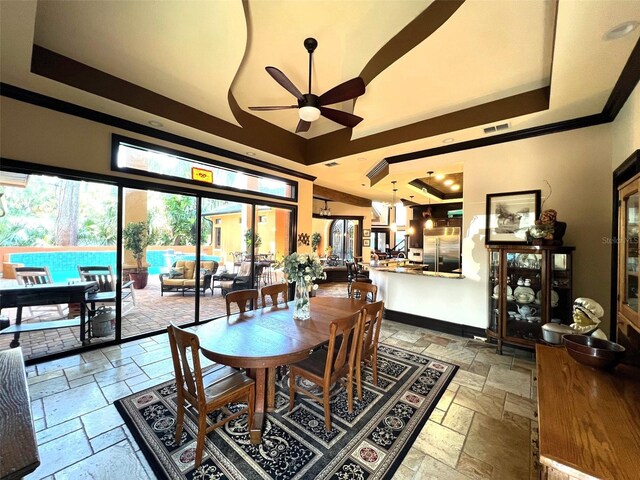 dining area with ceiling fan, a raised ceiling, and light tile patterned floors