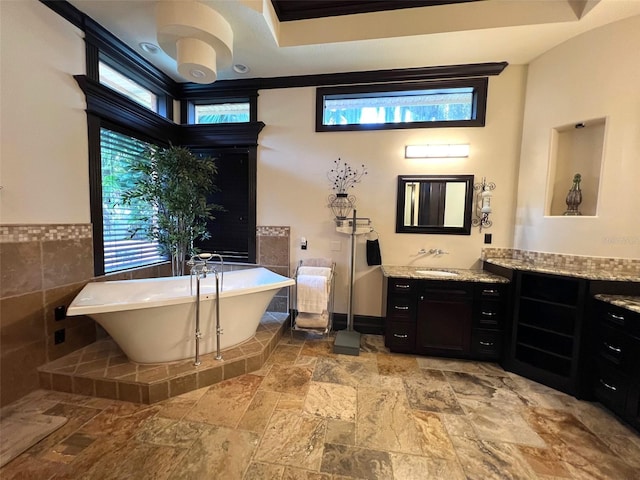 full bath with a freestanding tub, tile walls, and vanity