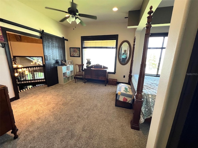 bedroom with light carpet, a barn door, and baseboards