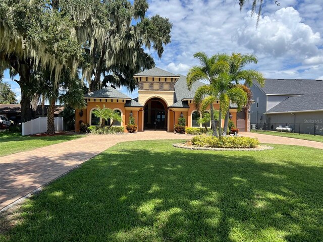 mediterranean / spanish home with a garage and a front lawn