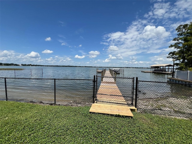 dock area with a water view, a gate, and a lawn