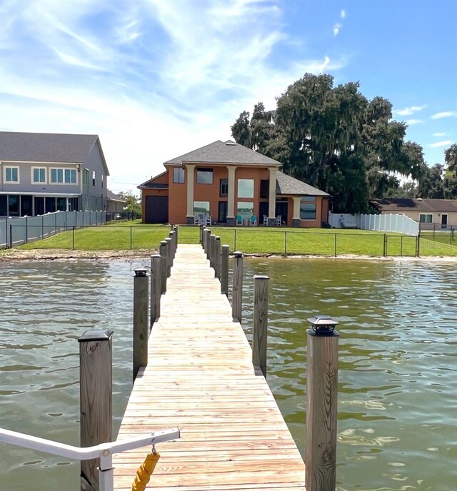 view of dock with a lawn and a water view