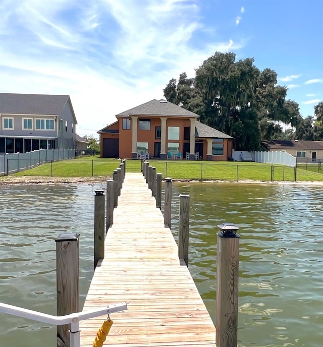 dock area featuring a water view, fence, and a yard