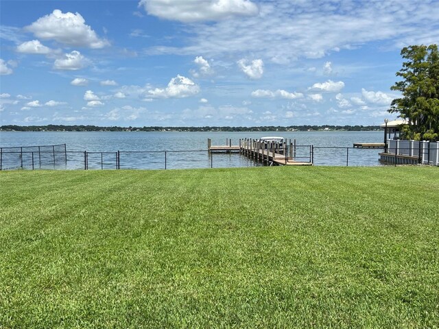 view of dock with a lawn and a water view