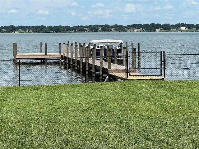 view of dock featuring fence, a lawn, and a water view