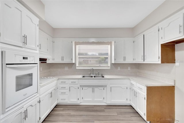 kitchen featuring oven, white cabinetry, and sink