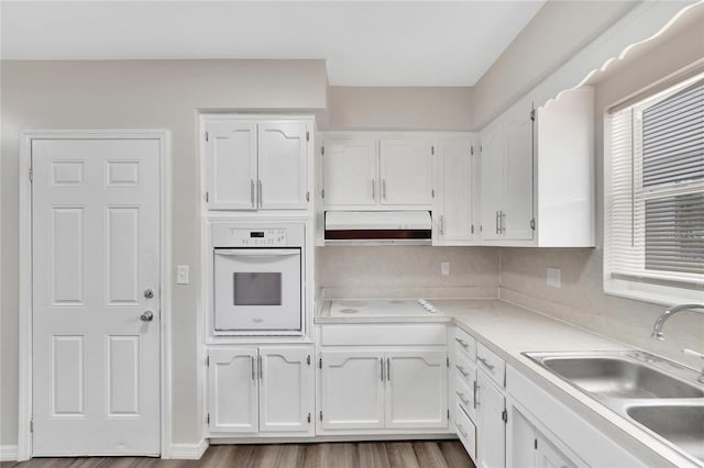 kitchen with white cabinets, white appliances, light hardwood / wood-style floors, and sink