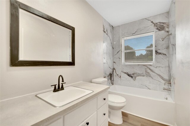 full bathroom featuring tiled shower / bath, toilet, hardwood / wood-style flooring, and vanity