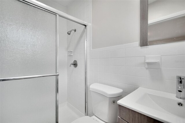 bathroom with vanity, toilet, walk in shower, and tile walls