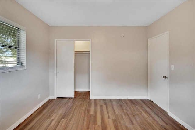 unfurnished bedroom featuring a closet, wood-type flooring, and a walk in closet