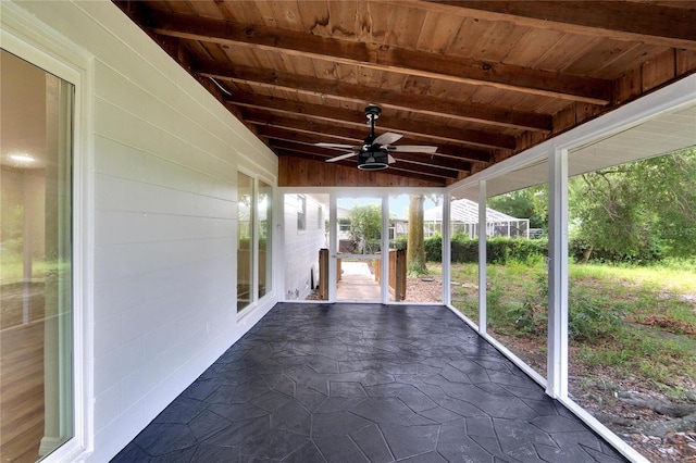 unfurnished sunroom featuring ceiling fan, lofted ceiling with beams, and wooden ceiling