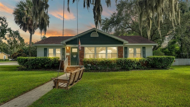 view of front of house featuring a yard, brick siding, and fence