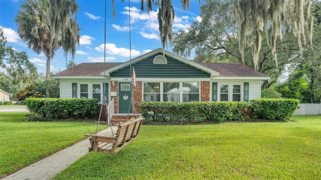 view of front of home with brick siding, a front yard, and fence