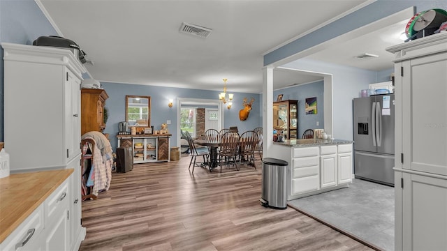 kitchen featuring light wood finished floors, stainless steel fridge, visible vents, white cabinets, and light countertops