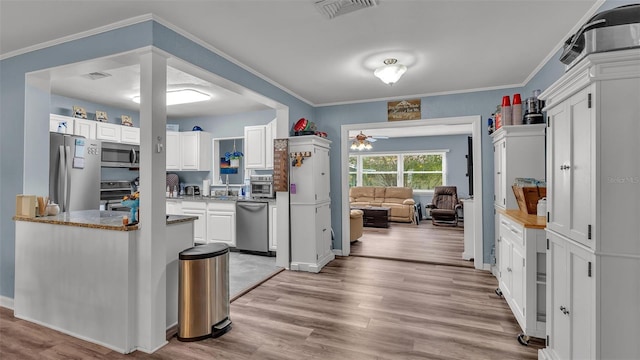 kitchen featuring stainless steel appliances, visible vents, white cabinets, light wood-type flooring, and crown molding