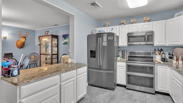 kitchen with stainless steel appliances, light stone countertops, visible vents, and white cabinetry