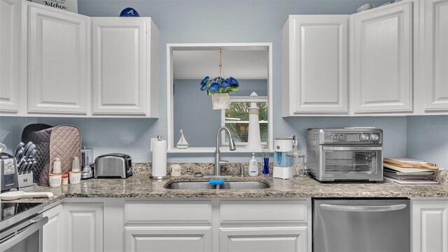 kitchen with stainless steel dishwasher, a sink, white cabinetry, and a toaster