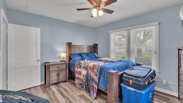 bedroom featuring a ceiling fan, light wood-style flooring, and baseboards