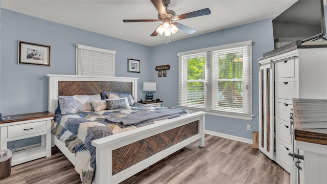 bedroom featuring a ceiling fan, baseboards, and wood finished floors