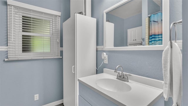 full bath featuring a textured wall and vanity