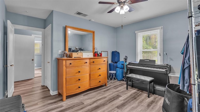 living area with a ceiling fan, baseboards, visible vents, and wood finished floors