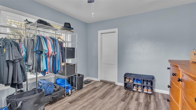 walk in closet with a ceiling fan and wood finished floors