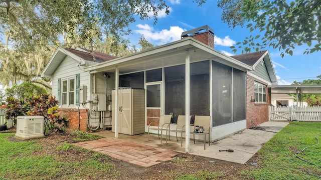 rear view of house featuring a chimney, a sunroom, a gate, a patio area, and fence