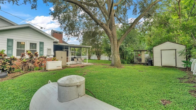 view of yard with an outdoor structure, fence, a storage shed, and a patio