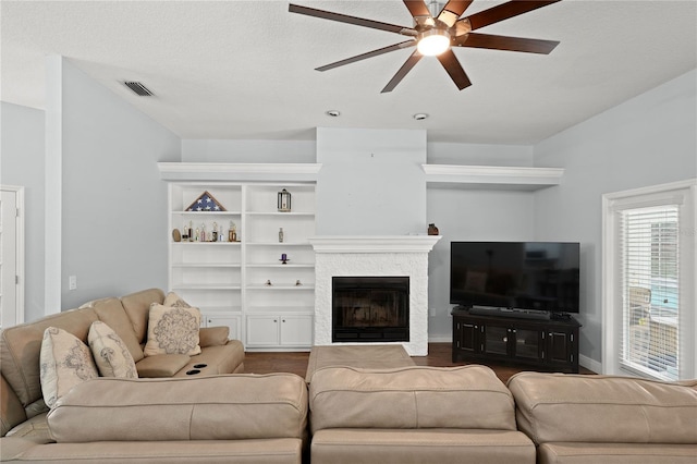 living room with a fireplace, wood-type flooring, a textured ceiling, and ceiling fan