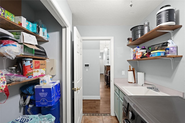 laundry area featuring sink, light tile patterned flooring, a textured ceiling, and washer / dryer