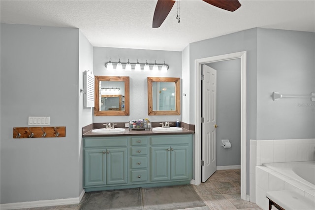 bathroom featuring vanity, a textured ceiling, ceiling fan, and tiled tub