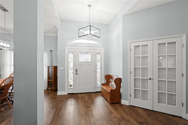 foyer with dark hardwood / wood-style floors, ornamental molding, and a notable chandelier