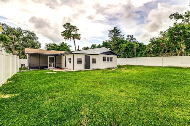 rear view of house featuring a sunroom, a yard, and a patio