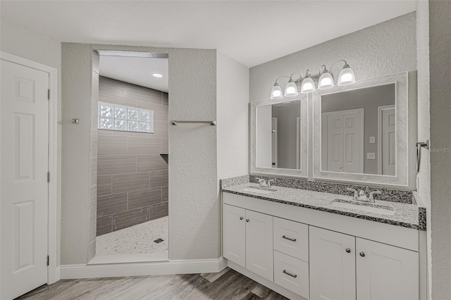 bathroom with a tile shower, vanity, and hardwood / wood-style floors