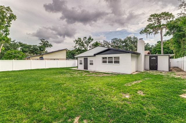 back of property featuring a shed and a yard