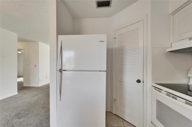 kitchen with stove, light colored carpet, extractor fan, white refrigerator, and white cabinetry