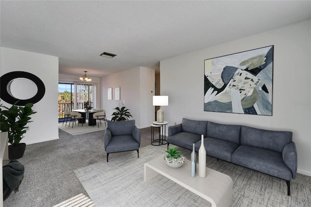 living room featuring carpet floors, a textured ceiling, and a notable chandelier