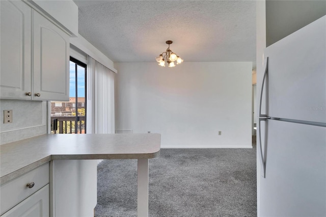 kitchen with white cabinets, decorative light fixtures, a textured ceiling, and white refrigerator