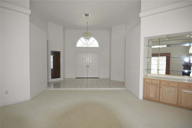 carpeted entrance foyer featuring a notable chandelier and a towering ceiling