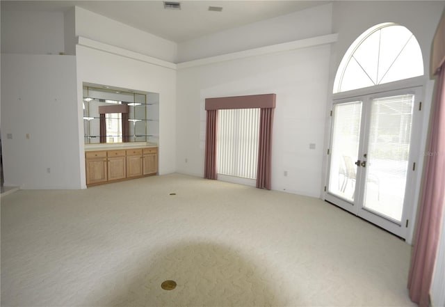 unfurnished living room featuring light colored carpet and french doors