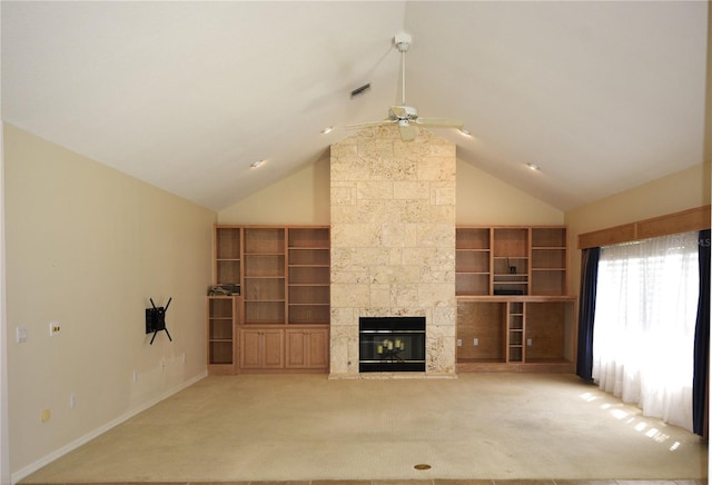 unfurnished living room featuring carpet flooring, built in shelves, vaulted ceiling, a stone fireplace, and ceiling fan