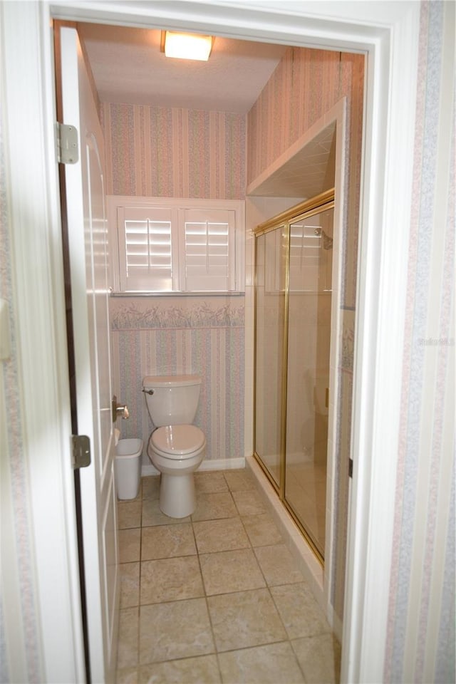 bathroom with tile patterned flooring, toilet, and an enclosed shower