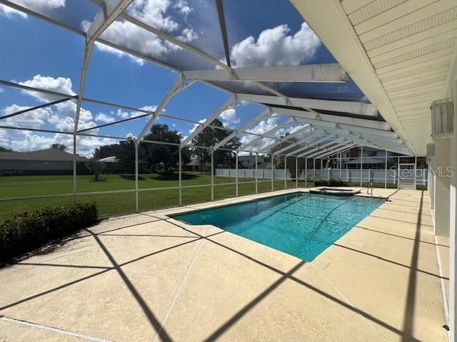 view of pool featuring glass enclosure, a yard, and a patio area