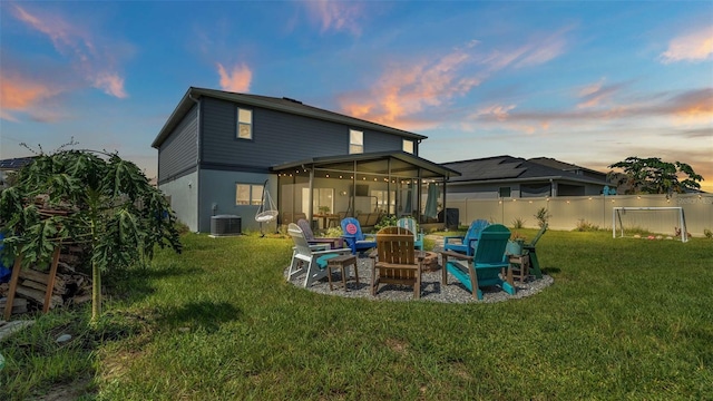 back house at dusk featuring a sunroom, a fire pit, a patio area, and a yard