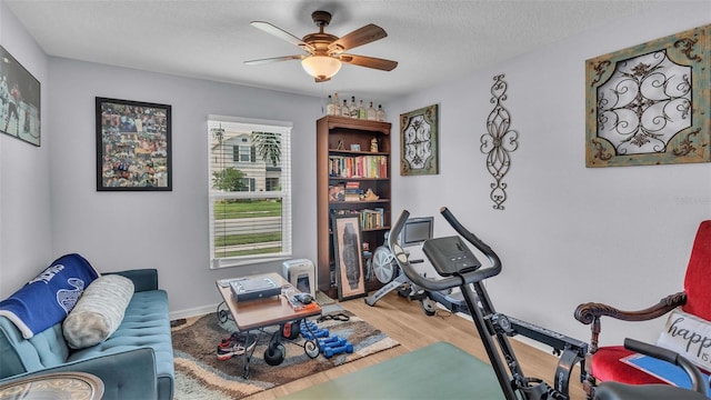 exercise area with ceiling fan, a textured ceiling, and hardwood / wood-style floors