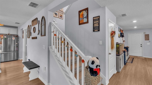 stairs with wood-type flooring and a textured ceiling