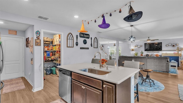 kitchen featuring an island with sink, dishwasher, light hardwood / wood-style flooring, dark brown cabinetry, and sink