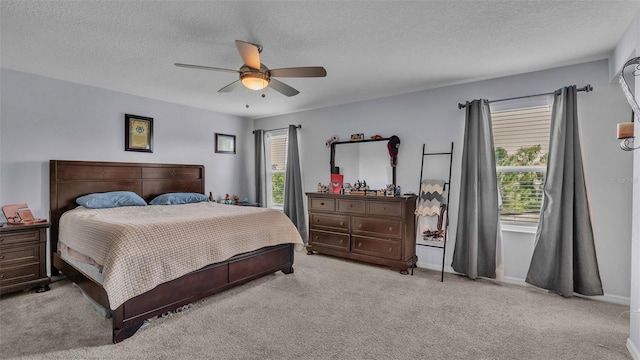 bedroom featuring multiple windows, a textured ceiling, ceiling fan, and light colored carpet