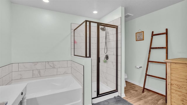 bathroom with shower with separate bathtub, toilet, and hardwood / wood-style flooring