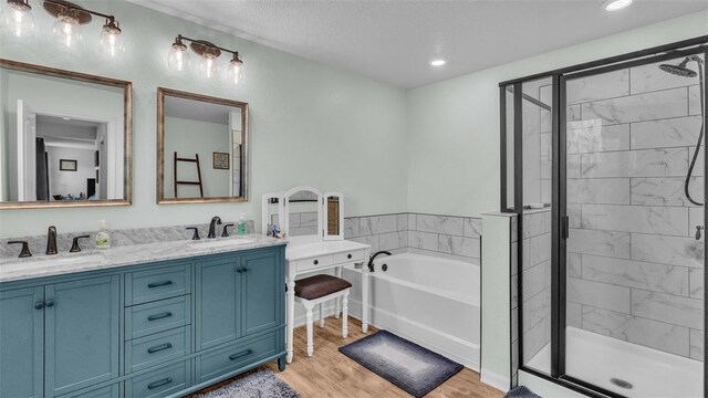 bathroom featuring a textured ceiling, wood-type flooring, vanity, and plus walk in shower